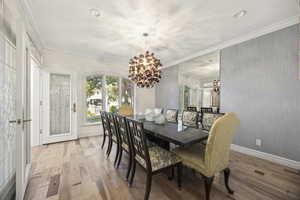 Dining space with ornamental molding, a chandelier, and light hardwood / wood-style floors