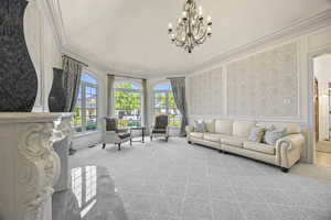 Carpeted living room with crown molding and a notable chandelier