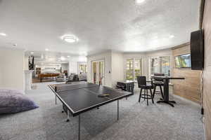 Rec room featuring pool table, wooden walls, crown molding, french doors, and a textured ceiling