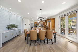 Dining room featuring sink, an inviting chandelier, crown molding, and light hardwood / wood-style flooring