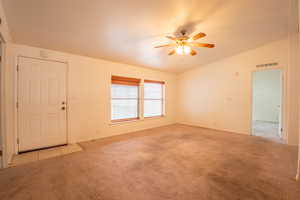 Unfurnished room with lofted ceiling, ceiling fan, and light carpet