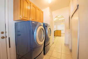 Washroom with washing machine and dryer, cabinets, and light tile patterned flooring