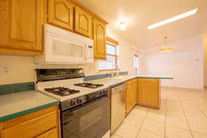 Kitchen featuring hanging light fixtures, lofted ceiling, kitchen peninsula, range with gas stovetop, and stainless steel dishwasher