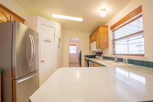 Kitchen with light brown cabinetry, sink, white appliances, and light tile patterned flooring