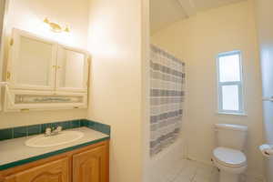 Full bathroom with vanity, toilet, tile patterned floors, and shower / bath combo with shower curtain