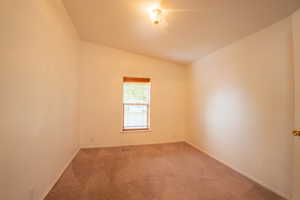 Carpeted spare room featuring lofted ceiling