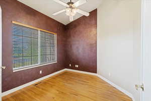 Empty room with hardwood / wood-style floors and ceiling fan