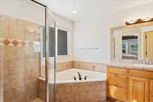 Bathroom featuring separate shower and tub and vanity