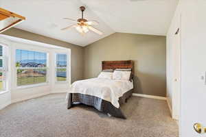 Carpeted bedroom featuring ceiling fan and vaulted ceiling