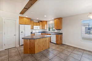 Kitchen with tile patterned floors, a kitchen island, sink, and white appliances