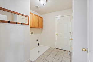 Washroom featuring hookup for a washing machine, cabinets, light tile patterned floors, and hookup for an electric dryer