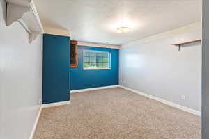 Empty room featuring a textured ceiling and carpet flooring