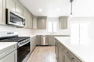 Kitchen featuring gray cabinetry, appliances with stainless steel finishes, light wood-style flooring, and a sink