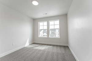 Empty room with carpet flooring, a textured ceiling, visible vents, and baseboards