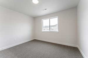 Spare room with visible vents, dark carpet, and baseboards