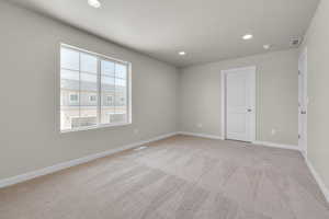 Empty room featuring a textured ceiling and light colored carpet