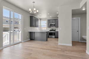 Kitchen with a wealth of natural light, kitchen peninsula, light wood-type flooring, and appliances with stainless steel finishes