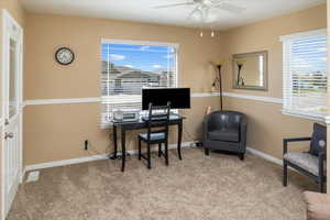 Home office with light carpet and ceiling fan