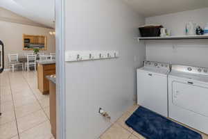 Clothes washing area with light tile patterned floors, a chandelier, and washer and clothes dryer