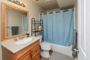 Full bathroom featuring tile patterned floors, shower / bath combination with curtain, toilet, and vanity