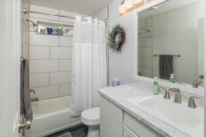 Full bathroom with vanity, toilet, hardwood / wood-style floors, and shower / bathtub combination with curtain