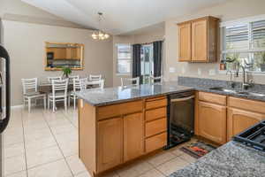 Kitchen with pendant lighting, black appliances, a notable chandelier, kitchen peninsula, and sink