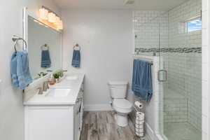 Bathroom with a shower with door, vanity, toilet, and hardwood / wood-style floors