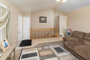 Living room with lofted ceiling, a textured ceiling, and tile patterned floors