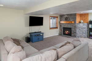 Carpeted living room featuring a textured ceiling and a fireplace