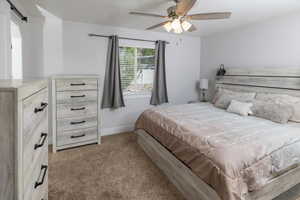 Carpeted bedroom featuring a barn door and ceiling fan