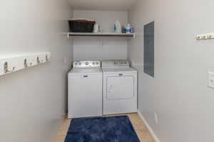 Laundry area featuring electric panel, light tile patterned flooring, and separate washer and dryer