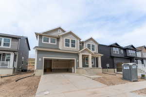 Craftsman-style house featuring concrete driveway, a porch, and an attached garage