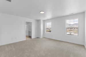 Empty room with light carpet and a textured ceiling