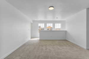 Unfurnished room with light colored carpet and a textured ceiling