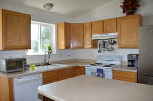 Kitchen featuring vaulted ceiling, white appliances, and sink