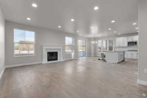 Unfurnished living room featuring a wealth of natural light, a notable chandelier, and light wood-type flooring