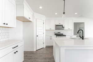 Kitchen featuring stainless steel appliances, a sink, dark wood finished floors, white cabinetry, and recessed lighting