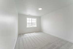 Unfurnished room with light carpet, baseboards, and a textured ceiling