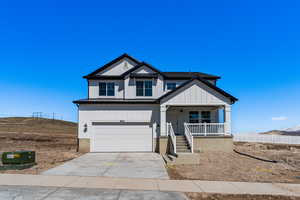 View of front of home with concrete driveway, a standing seam roof, metal roof, a porch, and a garage