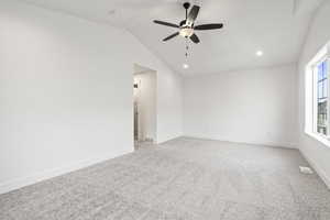 Unfurnished room featuring light carpet, lofted ceiling, a wealth of natural light, and ceiling fan