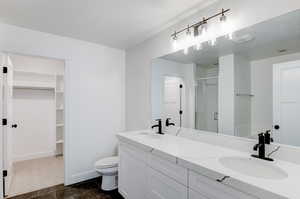 Bathroom featuring a textured ceiling, vanity, toilet, and walk in shower