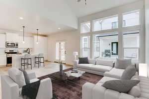 Living room with high vaulted ceiling, ceiling fan, sink, and light hardwood / wood-style flooring