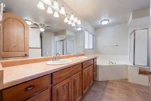 Bathroom featuring ceiling fan, vanity, and shower with separate bathtub