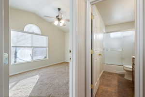 Full bathroom featuring combined bath / shower with glass door, a healthy amount of sunlight, vaulted ceiling, and ceiling fan