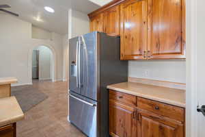 Kitchen featuring ceiling fan, stainless steel fridge with ice dispenser, and lofted ceiling