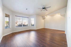 Empty room with ceiling fan, dark wood-type flooring, and vaulted ceiling