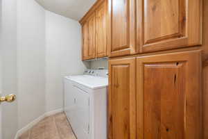 Laundry room with a textured ceiling, cabinets, and washer and dryer