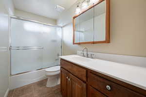 Full bathroom with toilet, enclosed tub / shower combo, and vanity