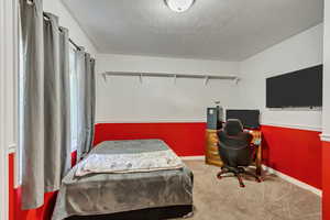 Bedroom with a textured ceiling and carpet floors