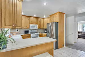 Kitchen featuring light carpet, white appliances, kitchen peninsula, and sink